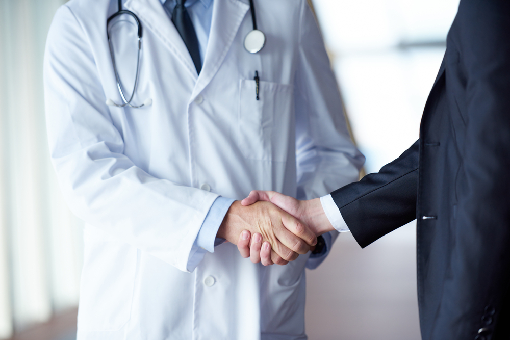 doctor handshake with a patient at doctors bright modern office in hospital