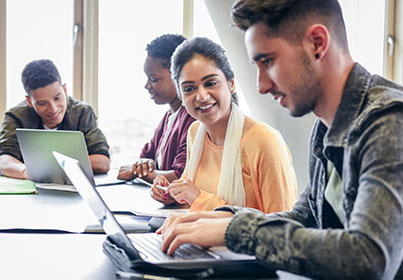 four students working on laptops