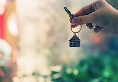 person holding keyring with house shaped key chain