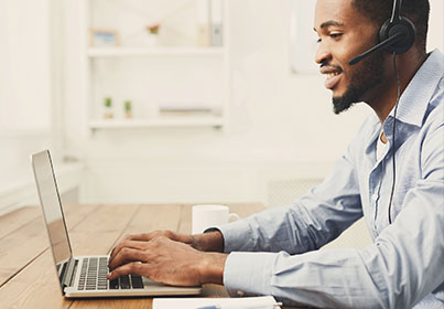 man working on laptop while wearing a headset